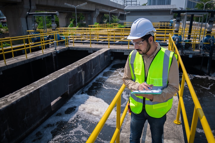 image of a man taking notes while doping inspection in an industrial establishment with water pump in the background