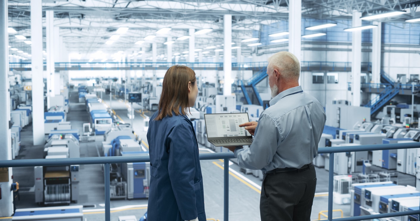 man-showing-woman-in-factory-laptop