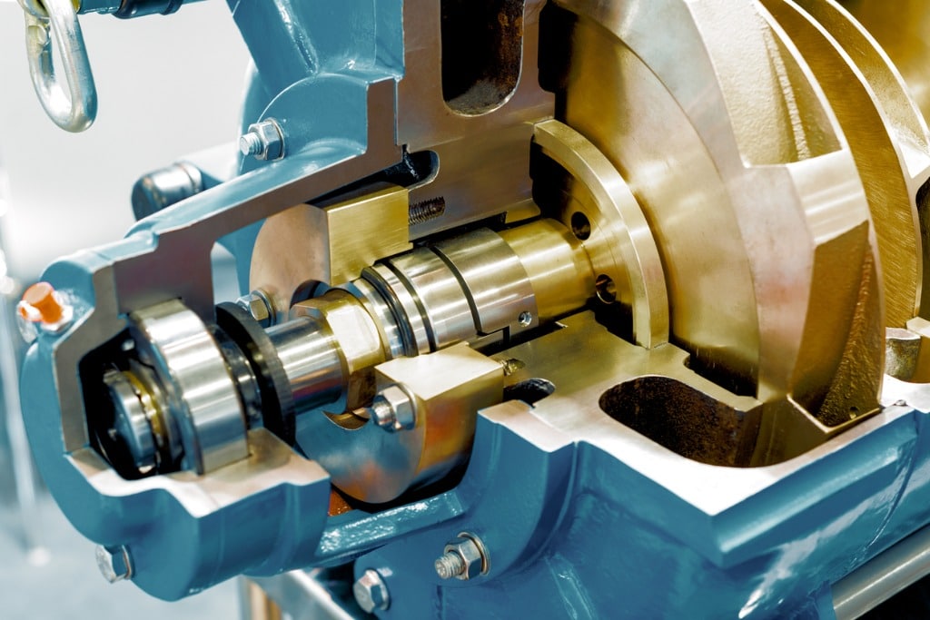 Close-up of a cutaway model of a mechanical pump. Visible are shiny metal components like gears and shafts, illustrating its internal workings.