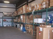 A warehouse interior with metal shelves stacked with various sized cardboard boxes and packages. The space is organized and well-lit, conveying efficiency.