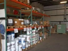 Shelves filled with various boxes, cans, and containers in a warehouse setting. Organized industrial space, calm and orderly atmosphere.